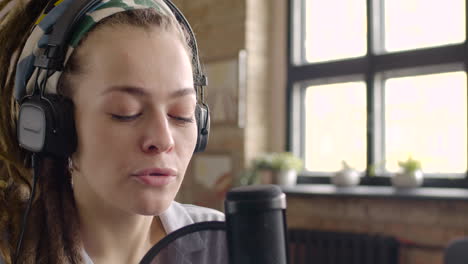 close up view of woman wearing headphones talking into a microphone while recording a podcast