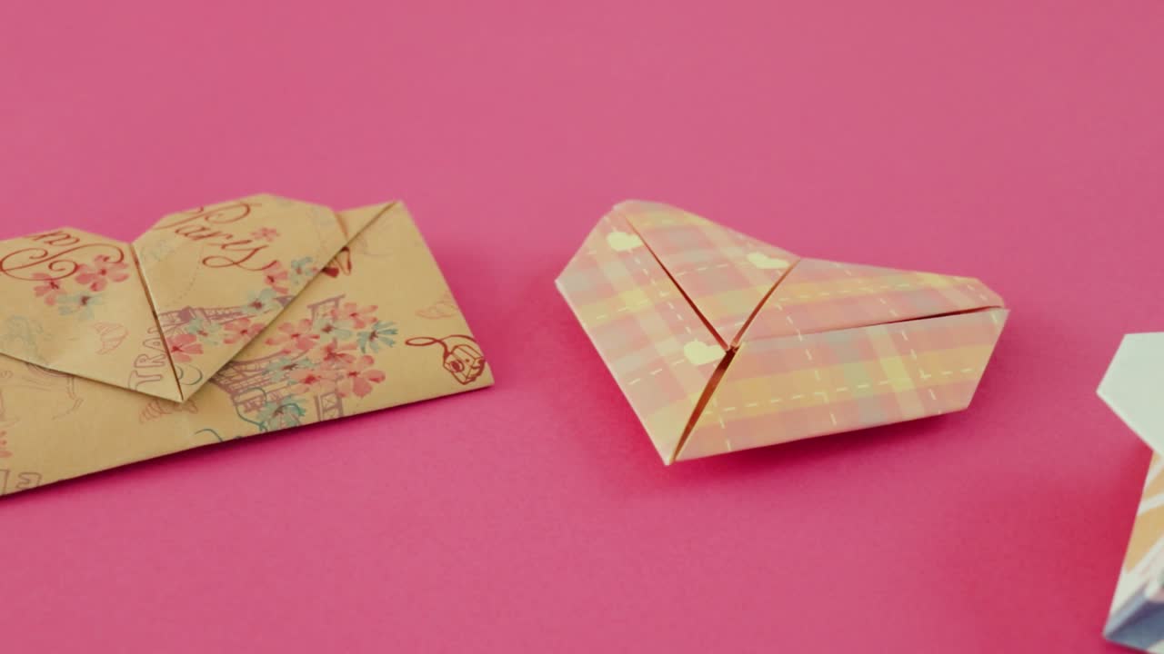 Folded heart shaped origami envelopes for Valentine on pink paper