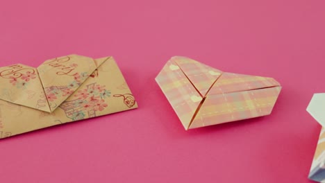 folded heart shaped origami envelopes for valentine on pink paper
