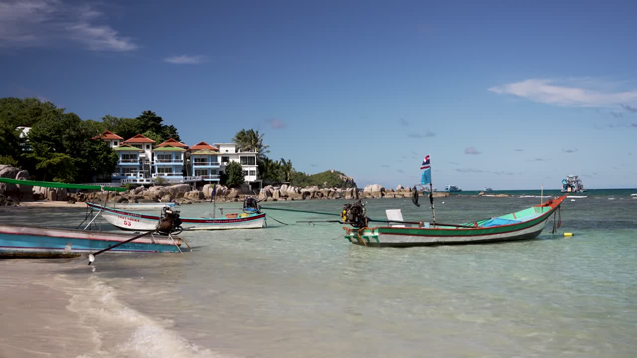 Empty longtail boats quietly moored in the shallow waters of Sairee Beach on Koh Tao, Thailand