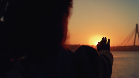 Girl-stretching-hand-silhouette-in-golden-sunlight-posing-rear-view-close-up.