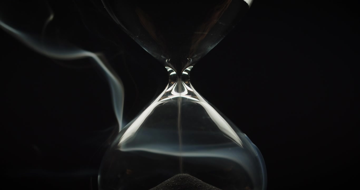 Smoke wraps an hourglass with black sand