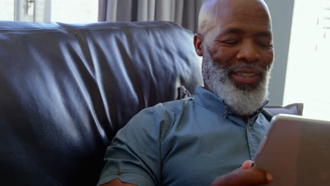 front view of mature black man using digital tablet in a comfortable home 4k