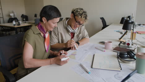 two colleagues collaborate on documents and charts at an office desk