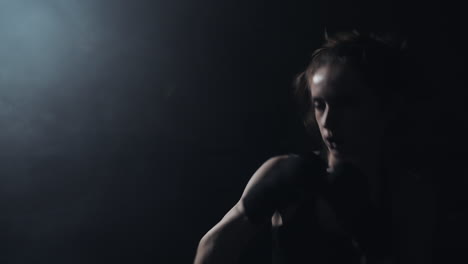 female boxer training in a dark, smoky gym with spotlight