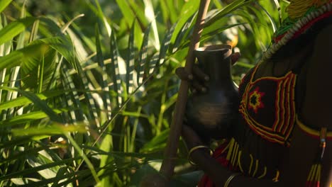 african woman in traditional clothes holding calabash in the jungle in uganda - close up