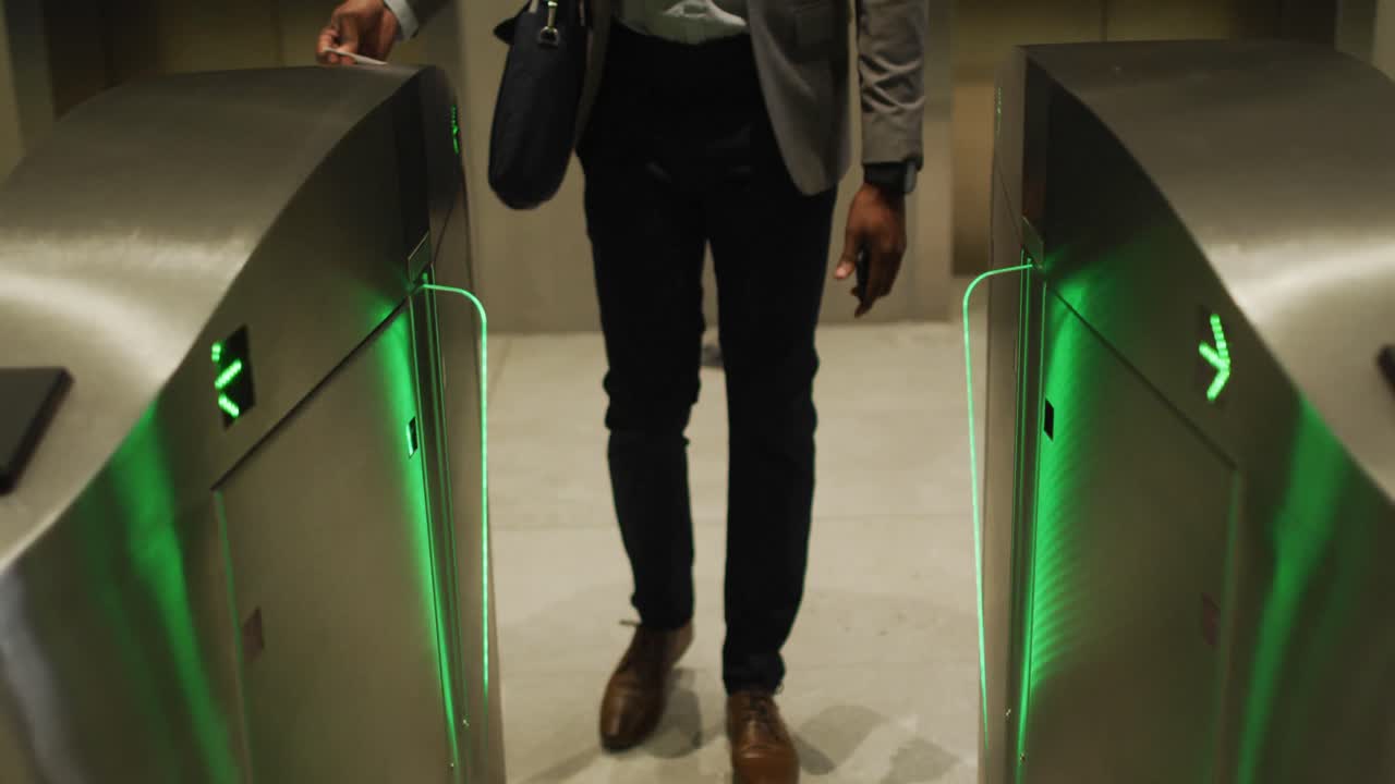 Midsection of african american businessman arriving in modern office using pass at security gates