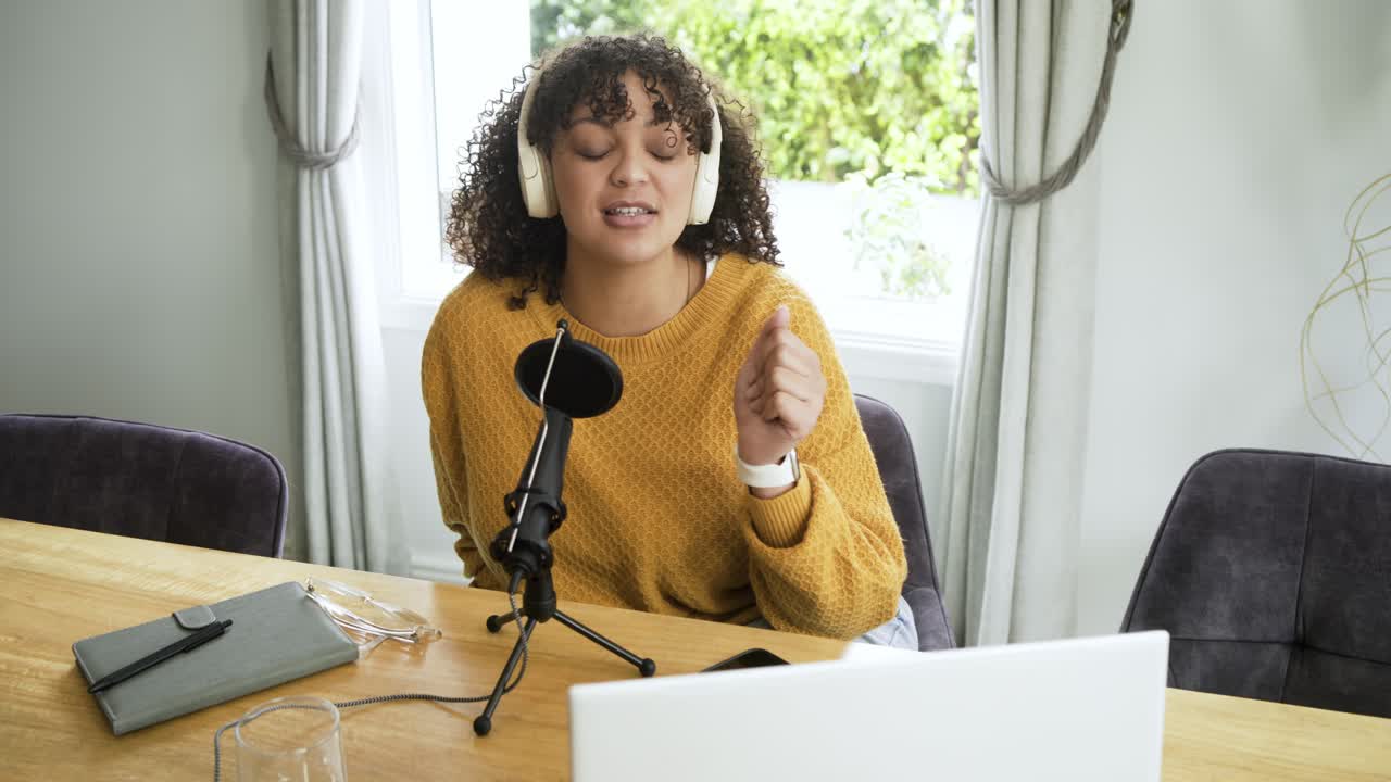 Szczęśliwa młoda kobieta nagrywająca podcast w domowym studiu