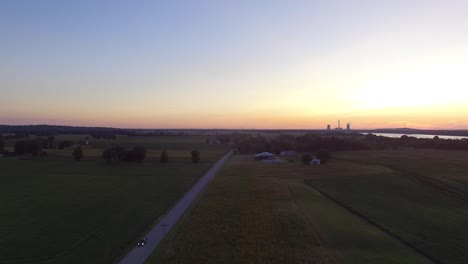 Car-drives-down-country-road-as-the-sun-sets