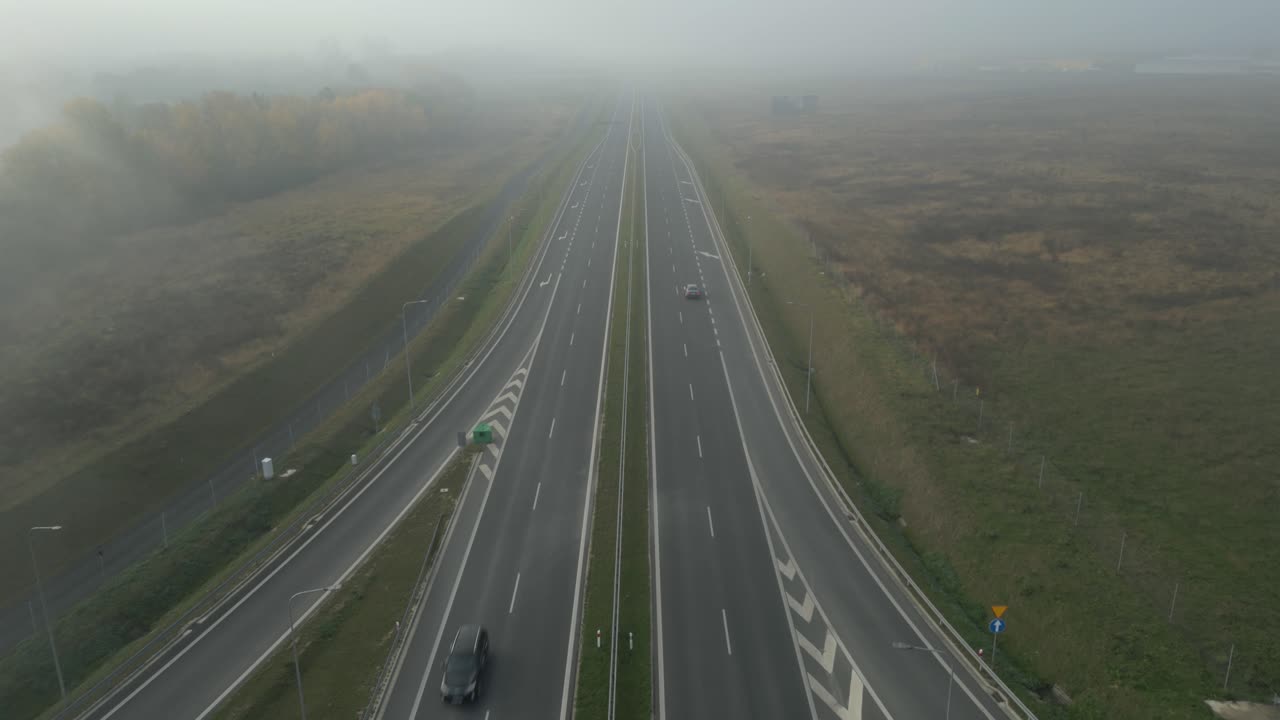 Empty highway disappearing into thick morning fog in a remote countryside landscape