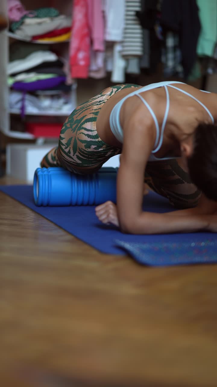 mujer haciendo una rutina de estiramiento con rodillo de espuma en casa