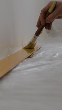 painting a wooden surface with golden paint