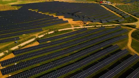 aerial footage of solar panels plant and wind turbines in a wind farm generating green electric energy on a wide green field on a sunny day, in taurage, lithuania, zooming out and descending shot