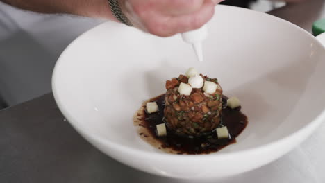 caucasian male chef decorating meal in kitchen, slow motion