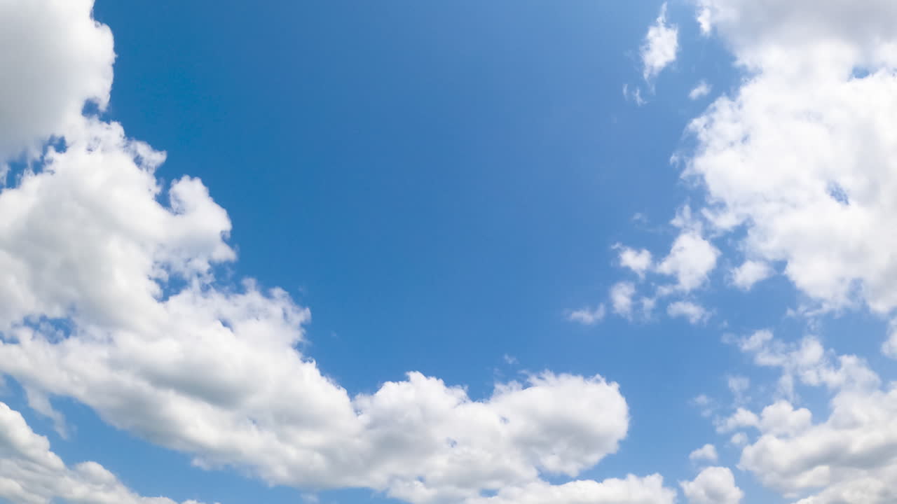 Azure summer sky with white fluffy clouds. Soft cloudscape in the atmosphere. Low angle view. Timelapse.
