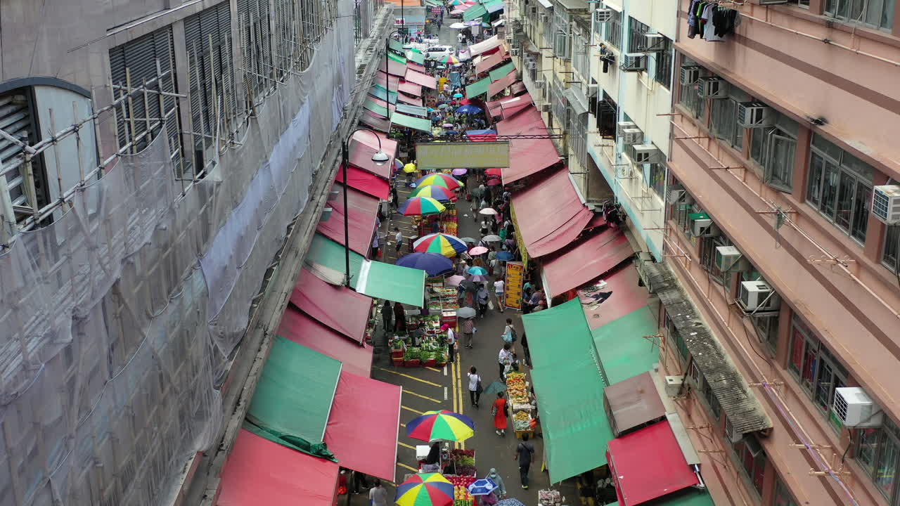 gente en el mercado de alimentos a lo largo de la calle en hong kong en un día lluvioso