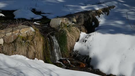 Una-Toma-De-Una-Pequeña-Cascada-En-La-Nieve-Sobre-Una-Pared-Muy-Baja