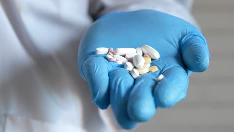 doctor holding assorted pills in blue gloves