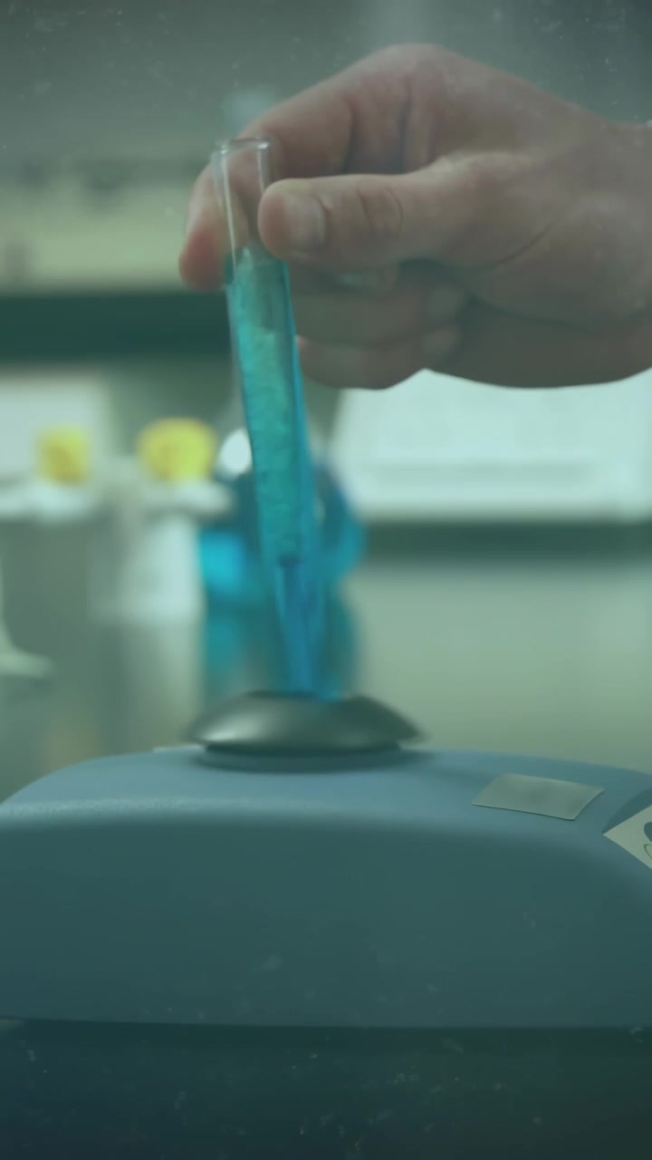 Vertical video: Hand approaching, placing blue tube into lab mixer, circles marking sample analysis
