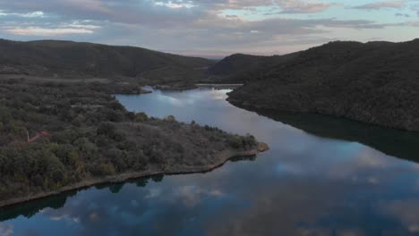 órbita aérea sobre el lago de montaña con una presa colorida puesta de sol colores árboles del bosque