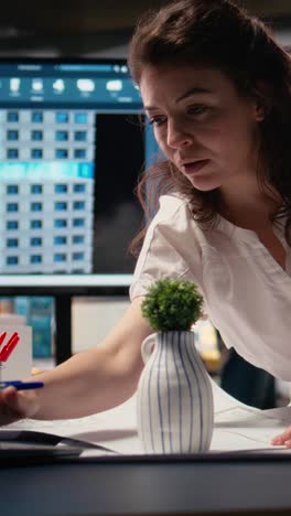 vertical video woman real estate engineer reviews city planning blueprints on laptop