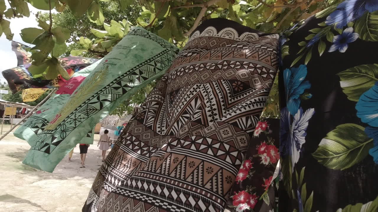 Multiple brightly colored bed sheets hanging out to dry on a washing line at the beach. close-up trucking shot