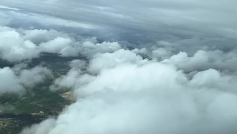 cockpit view overflying mallorca island, spain, between layers of white clouds, in a left turn