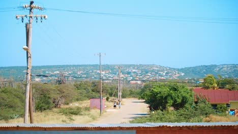 Two-young-girls-walking-through-the-outer-suburban-streets-in-Bonaire,-Caribbean