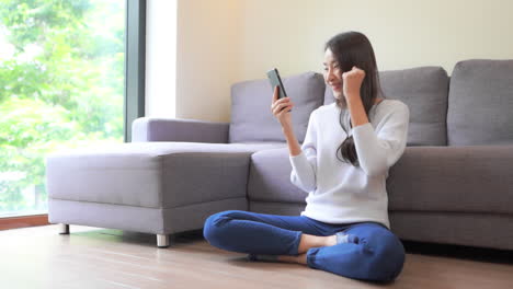 스마트폰을 사용할 때 환호하는 캐주얼하고 행복한 아시아 소녀