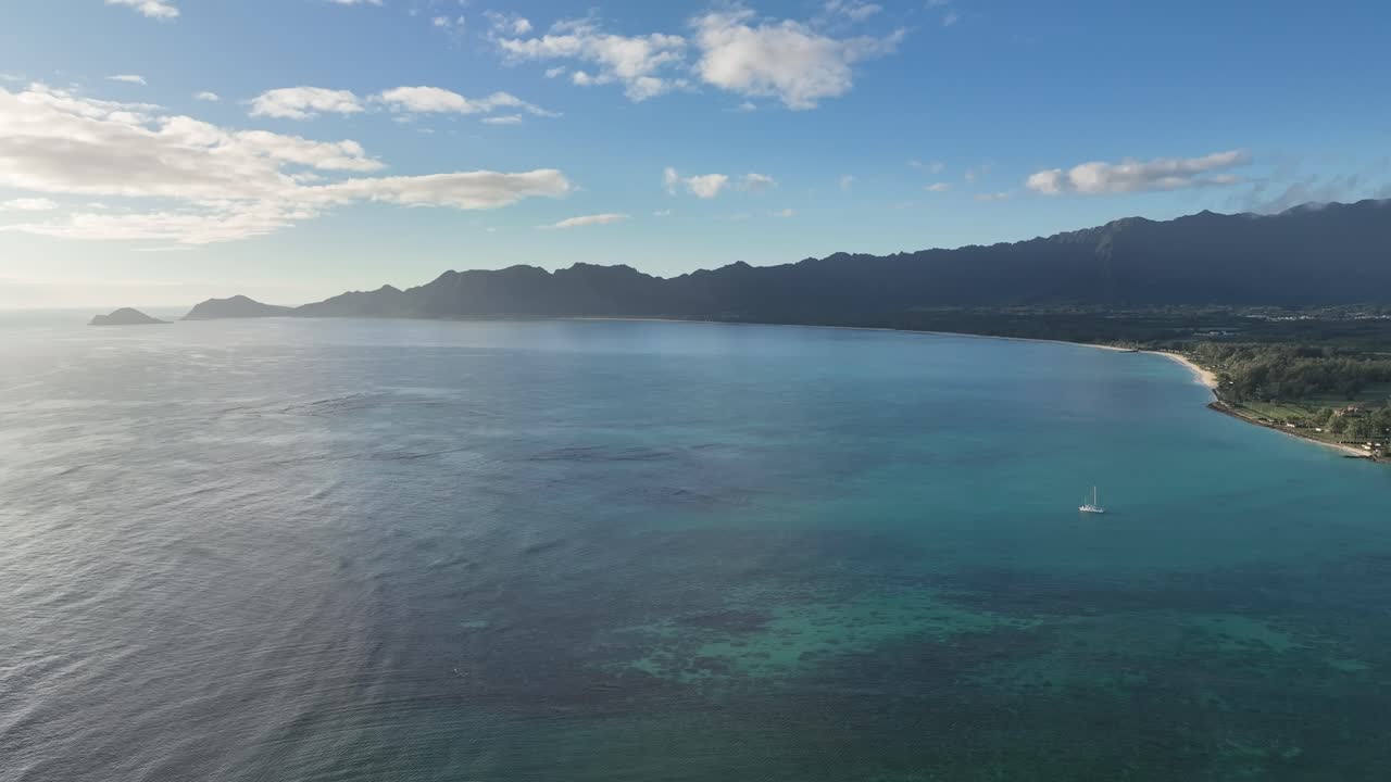slow mo 60 fps drone riprese aeree di waimanalo waimanalo spiaggia e baia mezzogiorno con oceano e barriera corallina barca acqua blu brillante montagne nuvole paradiso