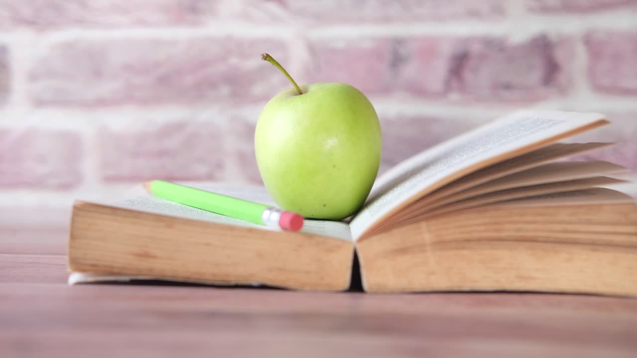 libro abierto con manzana y lápiz