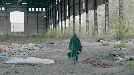 Radioactive zone. Human in safety uniform and gas mask in abandoned building with ruined walls and roof. Chemical attack. Air pollution.