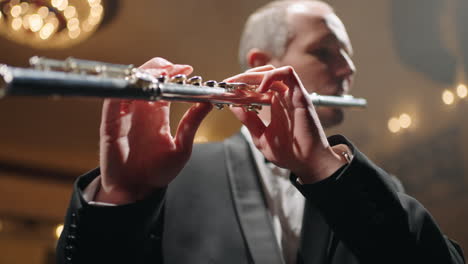 flutist in opera house musician is playing flute in symphonic orchestra or brass band