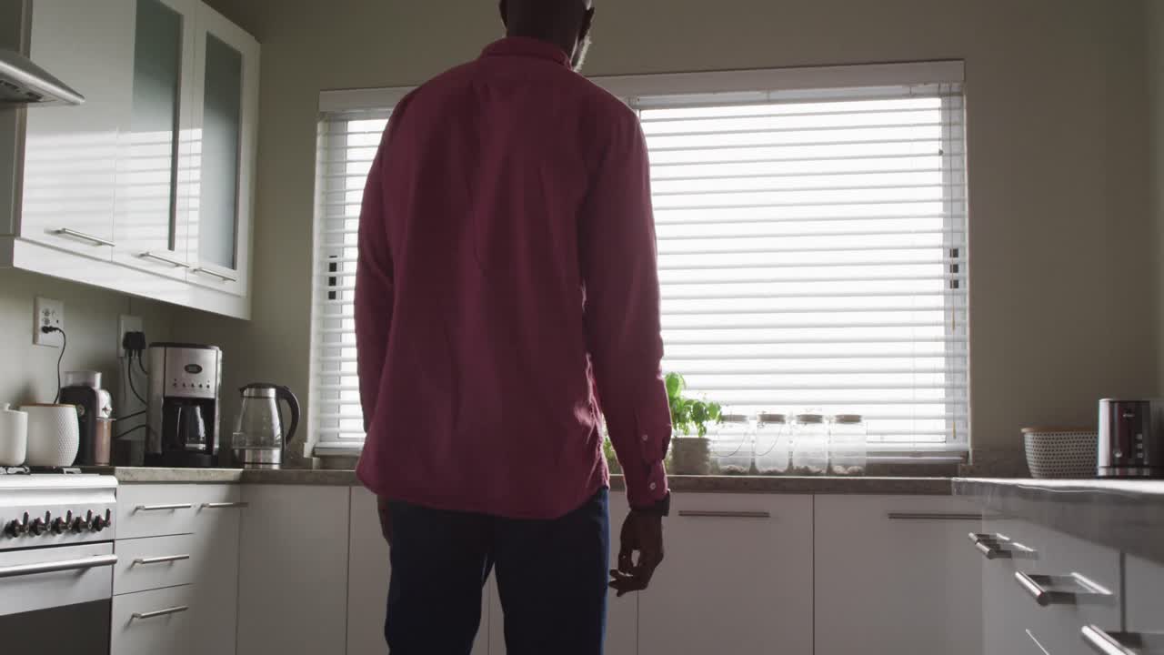 Video of back view of african american man walking in kitchen