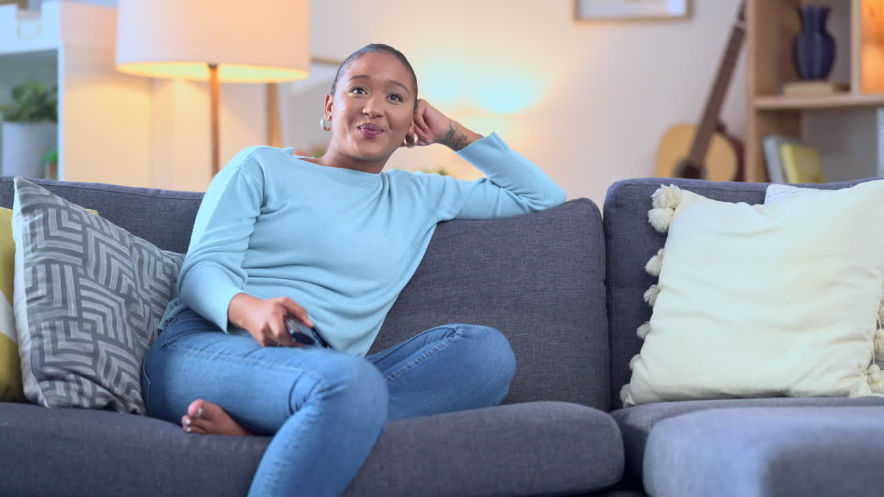 여자 가 소파 에서 휴식을 취 하고 tv 를 보고 있다