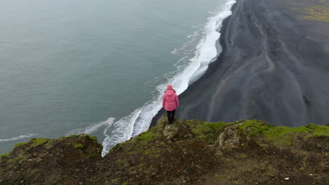 una mujer de pie sobre el promontorio de dyrholaey punto de vista en islandia