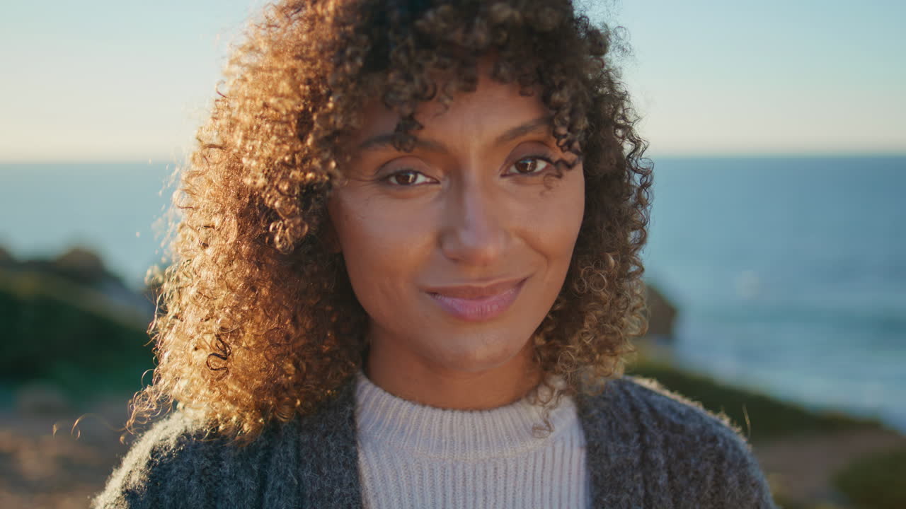 Portrait curly model posing in front evening seascape. Girl looking camera alone