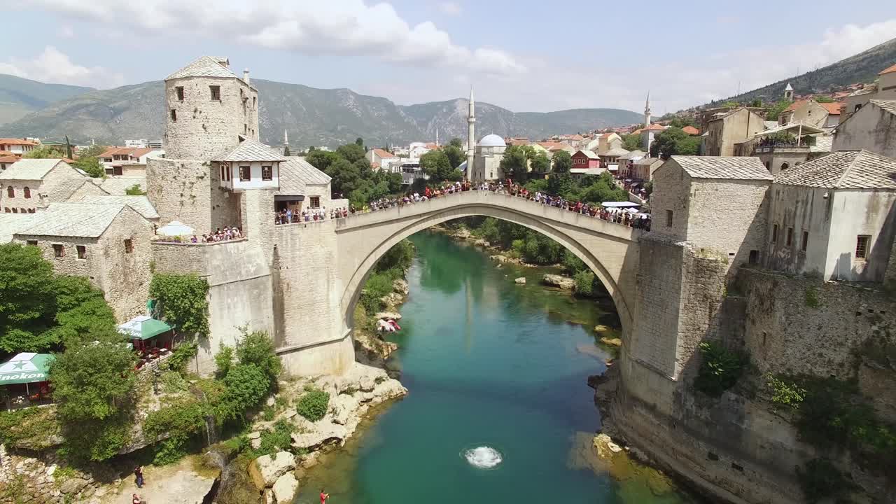 un hombre se zambulle desde el concurrido puente mostar hacia el río neretva abajo en mostar bosnia