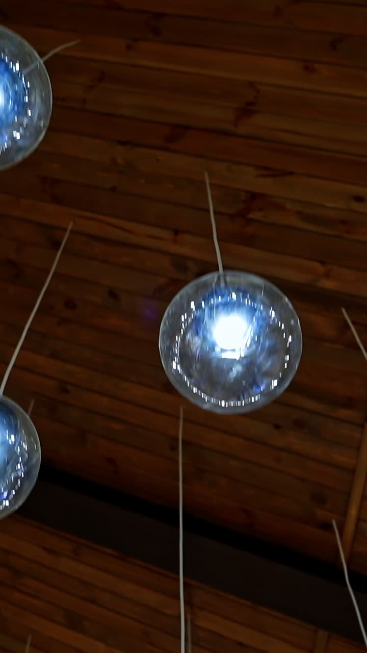 Modern ceiling lighting. Brown background with beautiful round glass ball lamps hanging on white wires. Luxury design of the room. Vertical video