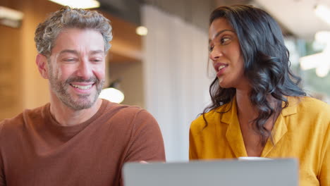mature male businessman with female colleague meeting at desk with laptop
