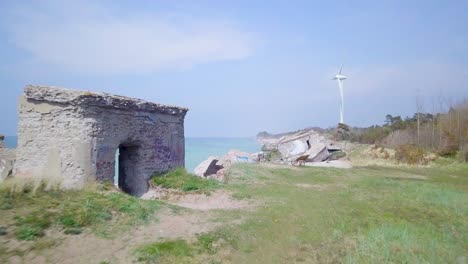 Aerial-view-of-abandoned-seaside-fortification-buildings-at-Karosta-Northern-Forts-on-the-beach-of-Baltic-sea-in-Liepaja,-Latvia,-calm-sea-on-a-sunny-day,-low-wide-angle-drone-shot-moving-forward