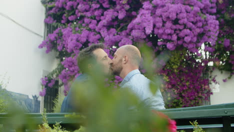 slow motion of homosexual men kissing on bench in summer park