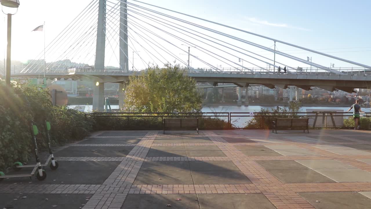 Slow walk up to a bench looking at the willamette river and the tilikum bridge in portalnd Oregon.