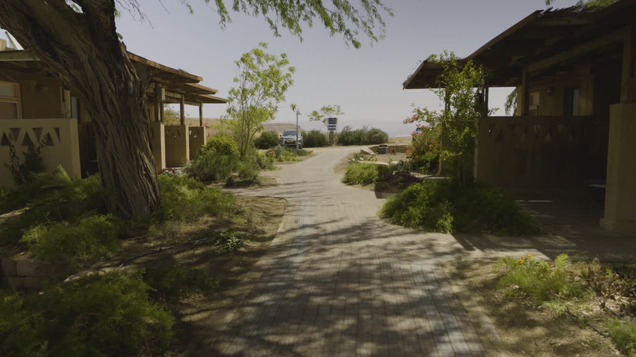 Peaceful walkway at Neot Smadar eco village, Israel, rustic homes, green plants, desert view and natural beauty.