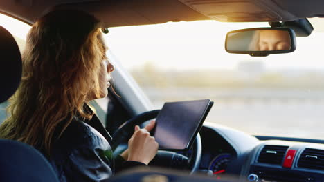 a young woman uses a tablet in the car navigating and orienting in an unfamiliar place 1