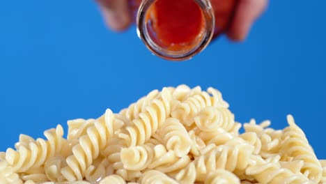 tomato sauce poured from the jar on boiled pasta fusilli.