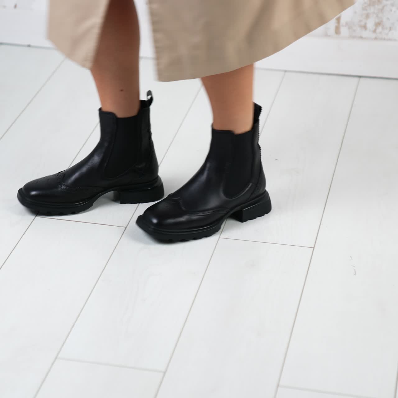 Funny dance in fashionable comfortable boots. Model moving in the studio to demonstrate stylish footwear. White backdrop