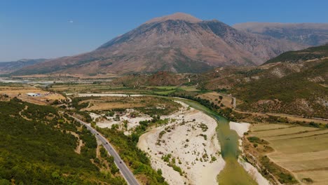 un río sinuoso atraviesa valles exuberantes y montañas escarpadas bajo un cielo azul claro en albania