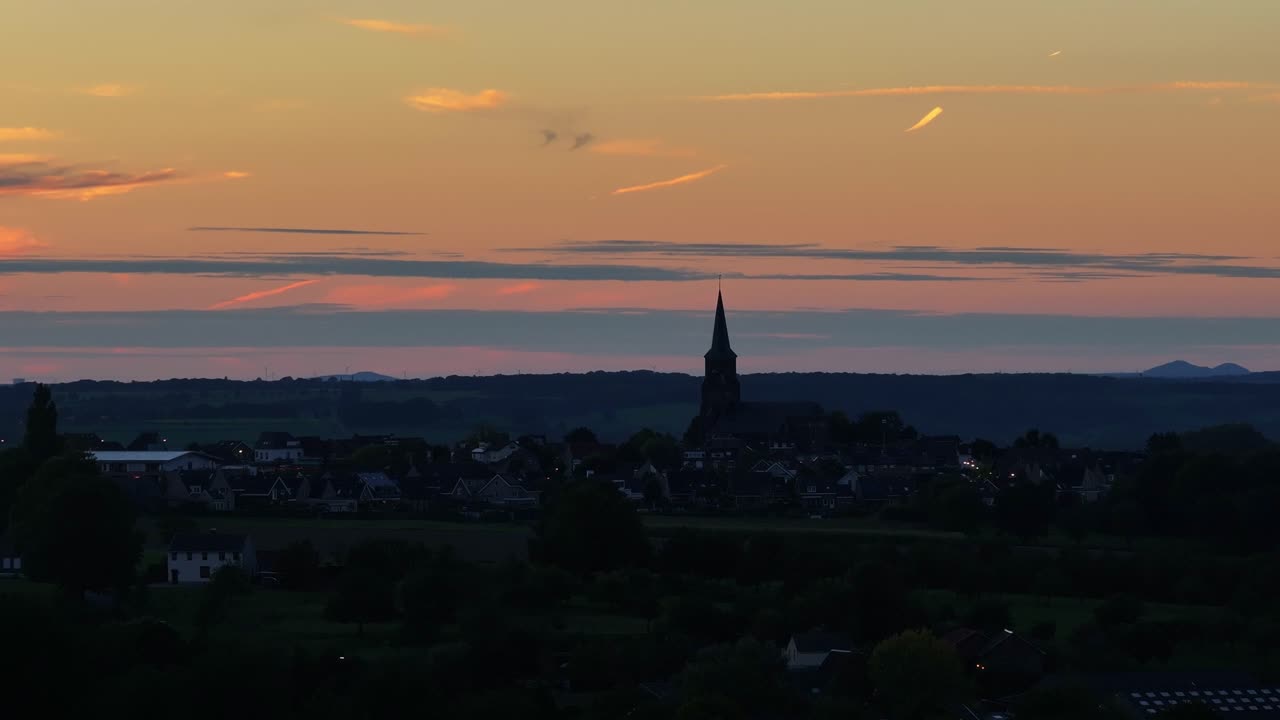 칼처럼, 높은 교회 첨탑은 기분이 좋지 않은 해가 지는 스카이 라인을 고 있습니다.
