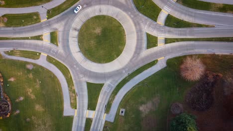 two cars entering and taking exits in a roundabout